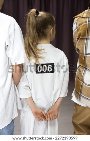 the child is sitting with his back. human. the child is standing with his back in a white T-shirt with a number