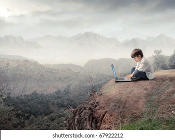 Kind, das sitzt und einen Laptop mit Landschaft auf dem Hintergrund verwendet