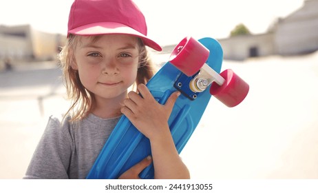 child with skateboard. girl in a red cap with a skateboard on the playground portrait. skateboarder child close-up outdoors sun glare. kid skateboarder looking at the camera lifestyle - Powered by Shutterstock