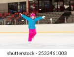 Child skating on indoor ice rink. Kids skate. Active family sport during winter vacation and cold season. Little girl in colorful wear training or learning ice skating. School sport activity and clubs