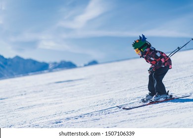 Child Skiing In Mountains. Active Teenage Kid With Safety Helmet, Goggles And Ski Poles Running Down Ski Slope.  Snowy Landscape, Sunny Day In Winter Season