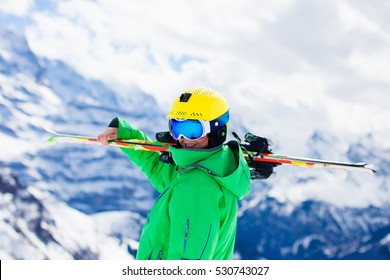 Child Skiing In Mountains. Active Teenager Kid With Safety Helmet, Goggles And Poles. Ski Race For Young Children. Winter Sport For Family. Kids Ski Lesson In Alpine School. Young Skier Racing In Snow