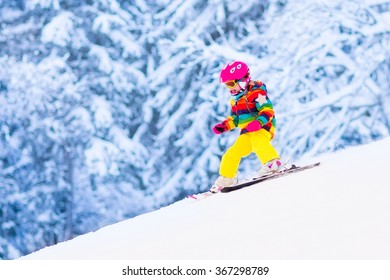 Child Skiing In Mountains. Active Toddler Kid With Safety Helmet, Goggles And Poles. Ski Race For Young Children. Winter Sport For Family. Kids Ski Lesson In Alpine School. Little Skier Racing In Snow