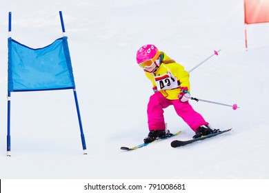 Child Skiing In Mountains. Active Toddler Kid With Safety Helmet, Goggles And Poles. Ski Race For Young Children. Winter Sport For Family. Kids Ski Lesson In Alpine School. Little Skier Racing In Snow