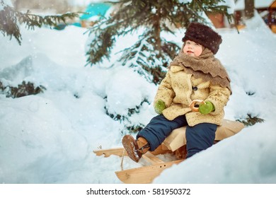 Child sledding. Toddler kid riding a sledge. Children play outdoors in snow. Kids sled in winter.  