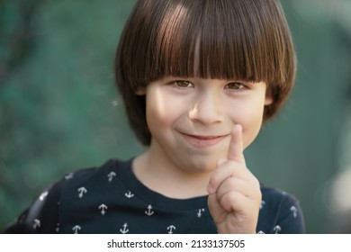 Child smiles and wags a finger, face portrait on blurry background