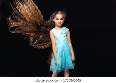 Child Smiling Girl With Extra Long And Volume Flying Hair. Fasion Model. Black Background. Blue Dress