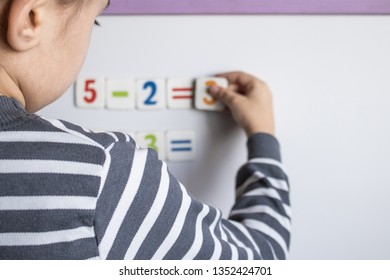 A child solves examples on a blackboard. The boy solves mathematical examples. The concept of education and school life.