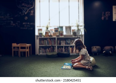 Child Solving Riddle In Book In School Library. Primary School Pupil Is Involved In Book With Riddles. Smart Girl Learning To Solve Problems. Benefits Of Everyday Practice. Child Curiosity