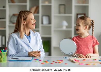 Child Specialist Making Tongue Exercises During Speech Therapy Session With Little Girl, Cute Preteen Female Kid With Stuttering Problem Having Meeting With Therapist Lady At Clinic, Closeup