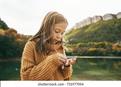 Child Spending Time By The Lake In Autumn. Kid Exploring Nature Near The Pond. Fall Weekend In The Open Air.