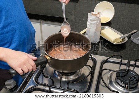 Child with a spoon checking the texture of brigadeiro, a Brazilian sweet.