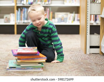 Child Stacking Favorite Books At The Library In The Children's Storytime Area.