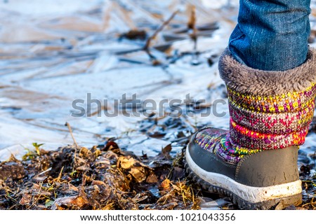 Child stands on frozen dirty puddle in the winter