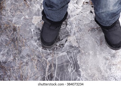 Child Steps On Frozen Puddle With Thin Ice.