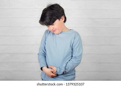 Child With Stomachache Against Brick Background