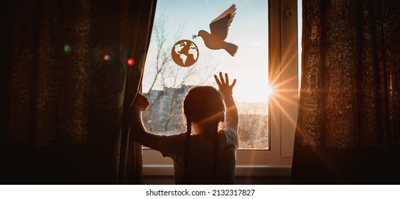 child stretches his hands sunlight sunset outside window flying dove world with branch forces globe. concept peace world, no war, ecology, protection planet Earth, pacifism