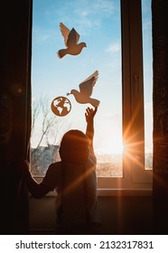 child stretches his hands sunlight sunset outside window flying dove world with branch forces globe. concept peace world, no war, ecology, protection planet Earth, pacifism