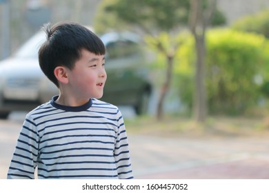 The child in striped clothes is smiling at something. - Shutterstock ID 1604457052