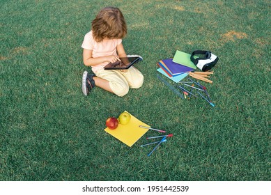 Child Study Exam Outside. Funny Kid Little Student Boy With Tablet, Sit On Lawn In Park, Studying At School Backyard