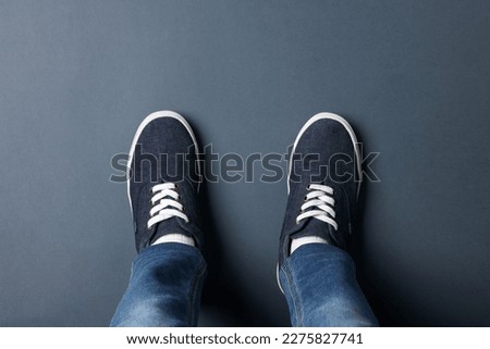 Child in stylish sneakers standing on grey background, top view
