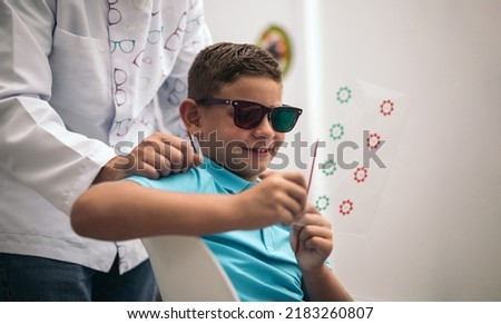 A child is subjected to some convergence-divergence cards with red and green glasses.vision therapy.