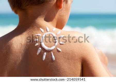 Child with suntan lotion shaped as a sun on his back at the beach concept for sun protection and skin care for children