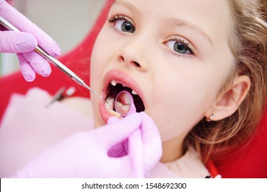 the child is a sweet little girl without front milk teeth in the dental chair. The dentist examines the teeth of the child's patient. Pediatric dentistry