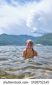 Child Swimming And Enjoing Holidays At The Lake Maggiore (Lombardy) In Italy. Active Girl On A Sunny Summer Day At The Lake.