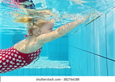 Child Swimming Lesson - Girl Learning To Dive Underwater In Pool. Healthy Active Family Lifestyle, Physical Exercise And Water Sports Activity With Parents On Summer Holiday With Kid In Aquatic Center