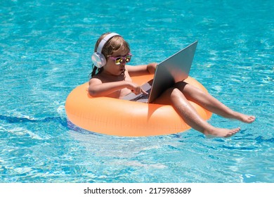 Child Swimming On An Inflatable Ring With A Laptop Water Pool. Child Online Study Or Working On Tropical Sea Beach. Technology For Life Concept.