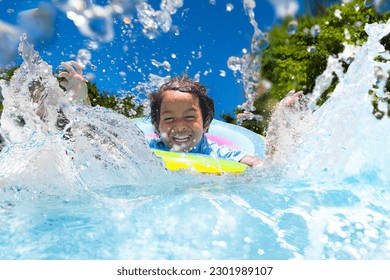 Child in swimming pool floating on toy ring. Kids swim. Colorful rainbow float for young kids. Little boy having fun on family summer vacation in tropical resort. Beach and water toys. Sun protection. - Shutterstock ID 2301989107