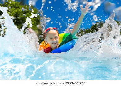 Child in swimming pool floating on toy ring. Kids swim. Colorful rainbow float for young kids. Little boy having fun on family summer vacation in tropical resort. Beach and water toys. Sun protection. - Powered by Shutterstock