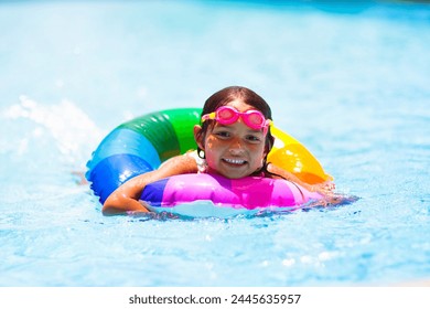 Child in swimming pool floating on toy ring. Kids swim. Colorful rainbow float for young kids. Little girl having fun on family summer vacation in tropical resort. Beach water toys. Sun protection. - Powered by Shutterstock