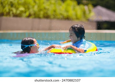 Child in swimming pool floating on toy ring. Kids swim. Colorful rainbow float for young kids. Little boy having fun on family summer vacation in tropical resort. Beach and water toys. Sun protection. - Powered by Shutterstock