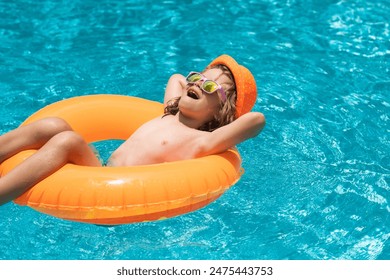 Child in swimming pool on inflatable float ring. Water toy, healthy outdoor sport activity for children. Kids beach fun. Child splashing in summer water pool.