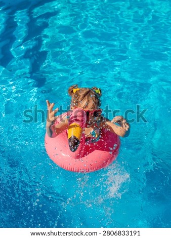 A child swims in a pool surrounded by flamingos. Selective focus. kid.