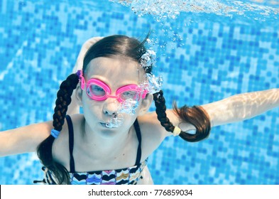 Child Swims In Swimming Pool Underwater, Happy Active Girl Dives And Has Fun Under Water, Kid Fitness And Sport On Family Vacation
