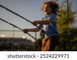 Child swing on city playground. Kids play public city park playground. Kid swinging. Summer activity for children. Kid on chain swing. Carefree and freedom childhood. Child swinging.