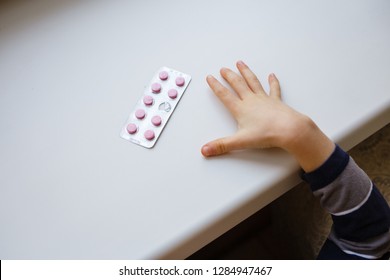 Child Takes Pack Of Pills. Dangerous Situation. A Small Child Curious About A Prescription Drug Container Illustrating The Importance Of Drug Safety And Parental Supervision And Communication.