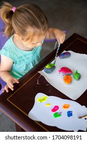 Child In A Teal Shirt Painting Rocks Colorful Colors, Art Activity For A Young Toddler Or Older Child