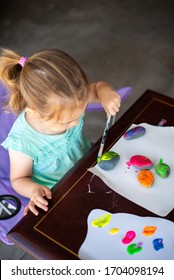 Child In A Teal Shirt Painting Rocks Colorful Colors, Art Activity For A Young Toddler Or Older Child