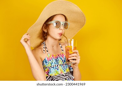 Child teenager girl in swimsuit, straw hat and sunglasses with lemonade metal straw in studio on yellow background, summer mood, - Powered by Shutterstock