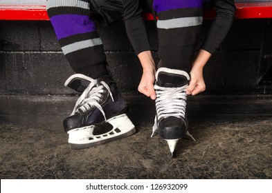 A child ties hockey skates in arena dressing room