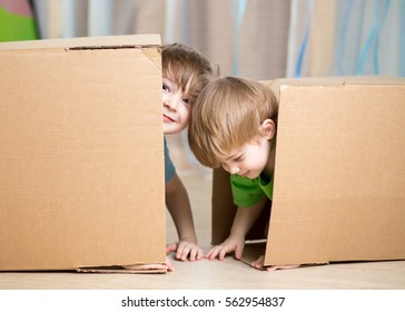 Child and toddler brothers playing in cardboard boxes