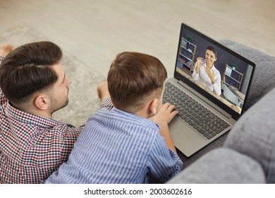 Child Together With Father Looking At Laptop Screen While Having Virtual Class In Covid19 Corona Virus Times. Little Elementary School Kid Learning English Letters With Online Teacher Or Private Tutor