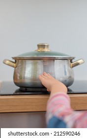 Child Touches Hot Pan On The Stove. Dangerous Situation At Home. 