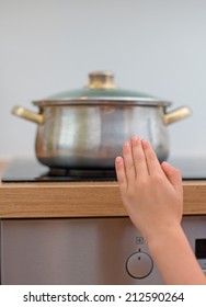 Child touches hot pan on the stove. Dangerous situation at home. 