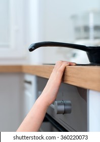 Child Touches Hot Pan On The Stove. Dangerous Situation At Home.