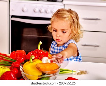 Child Touching Vagetable In Colander At Kitchen.